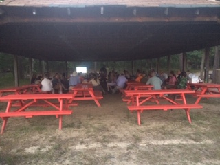A crowd of people sitting at red picnic tables